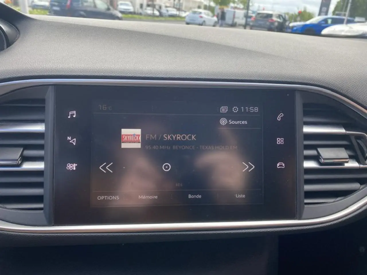 Écran tactile central de la Peugeot 308 SW 2018 affichant la radio FM Skyrock dans un intérieur gris sobre.