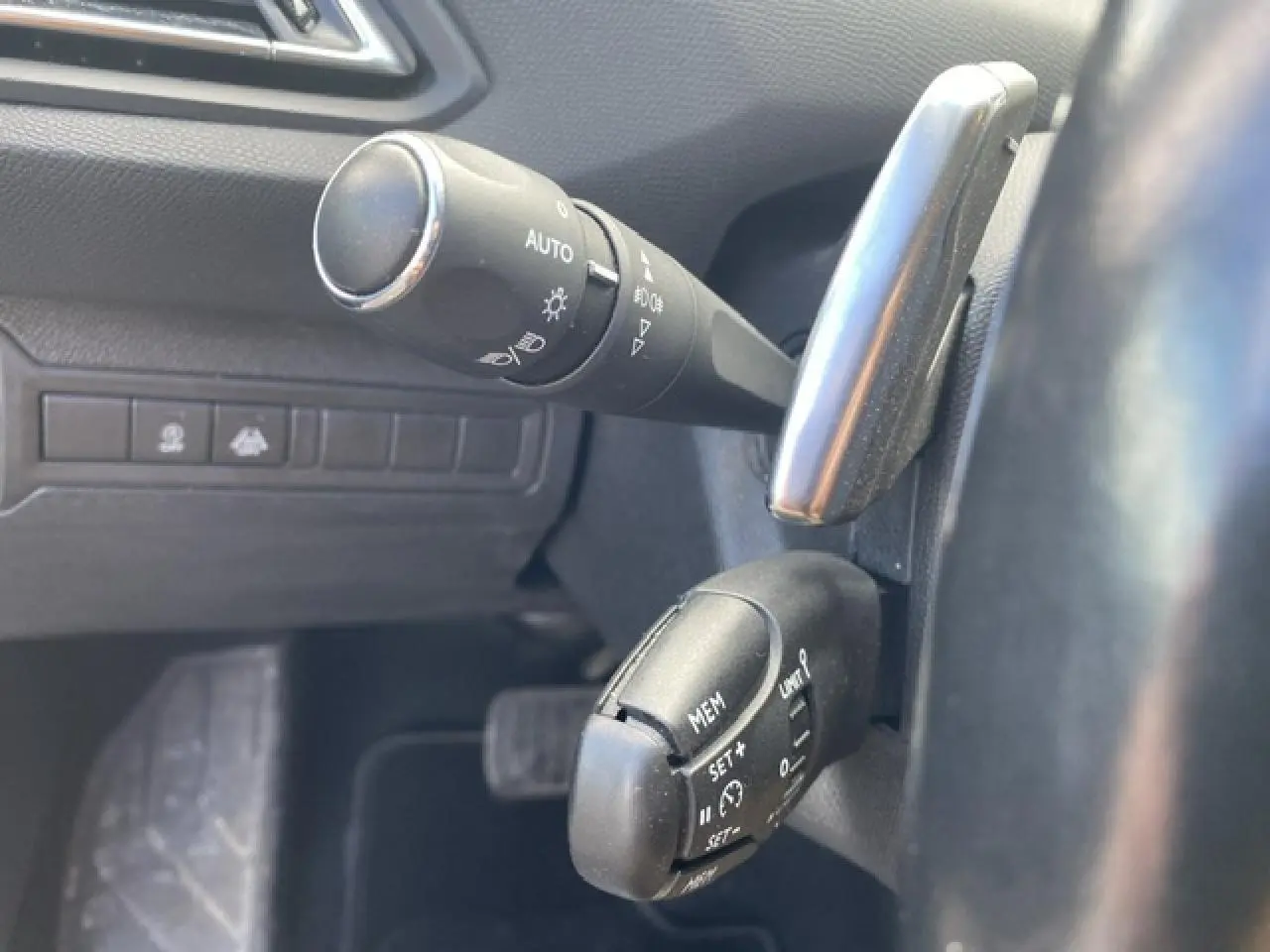 Gros plan sur les commandes de régulateur de vitesse et éclairage à gauche du volant d'une Peugeot 308 SW 2018.