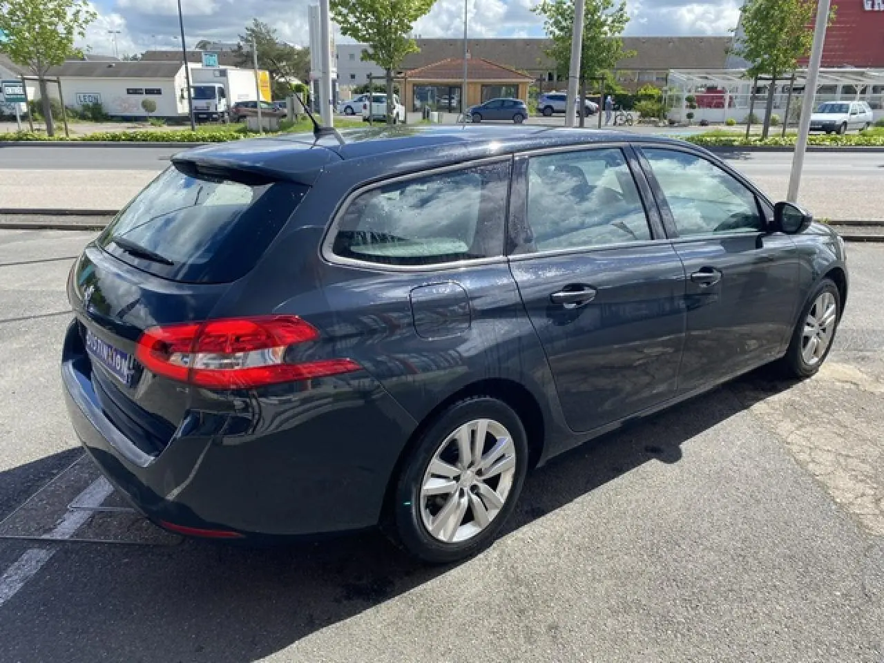 Peugeot 308 SW gris hurricane vue 3/4 arrière côté gauche, avec jantes alliage et feux arrière distinctifs.