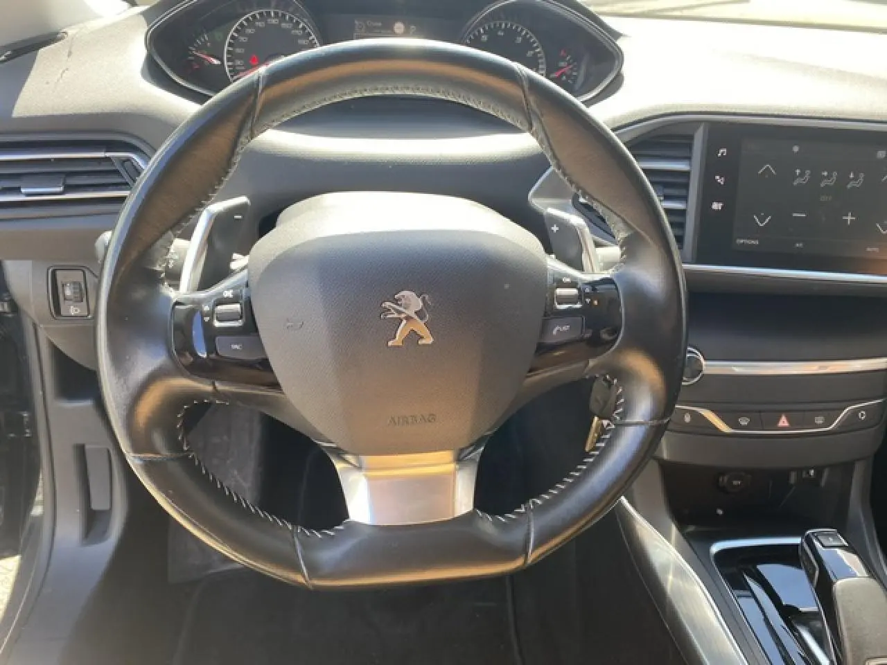 Vue rapprochée du volant cuir noir et du tableau de bord avec écran tactile de la Peugeot 308 SW gris Hurricane de 2018.