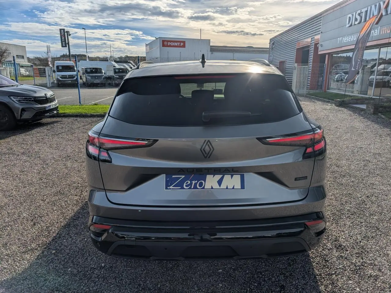 Vue arrière d’un Renault Austral gris métallisé avec feux LED fins et logo noir brillant sur un parking extérieur.