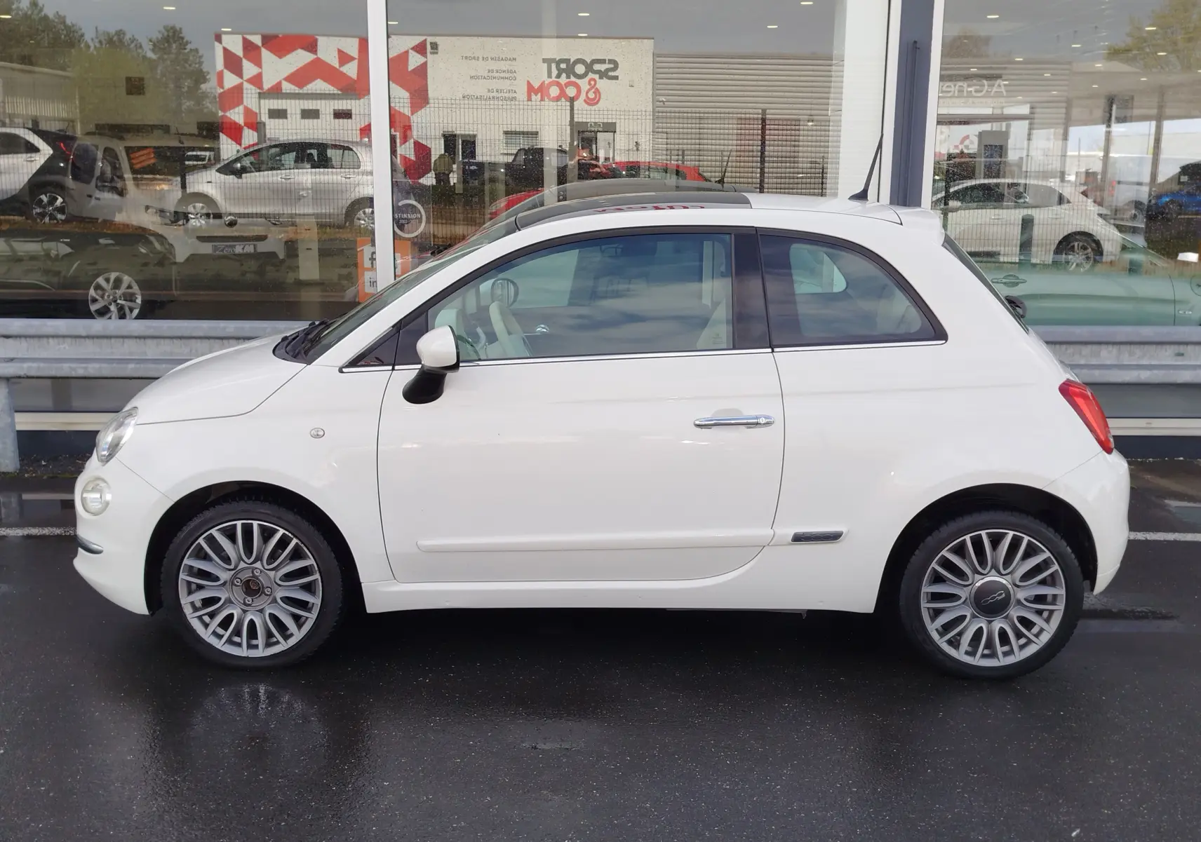 Vue de profil côté gauche d'une Fiat 500 Lounge blanche Bossa Nova avec jantes alliage et toit ouvrant panoramique.