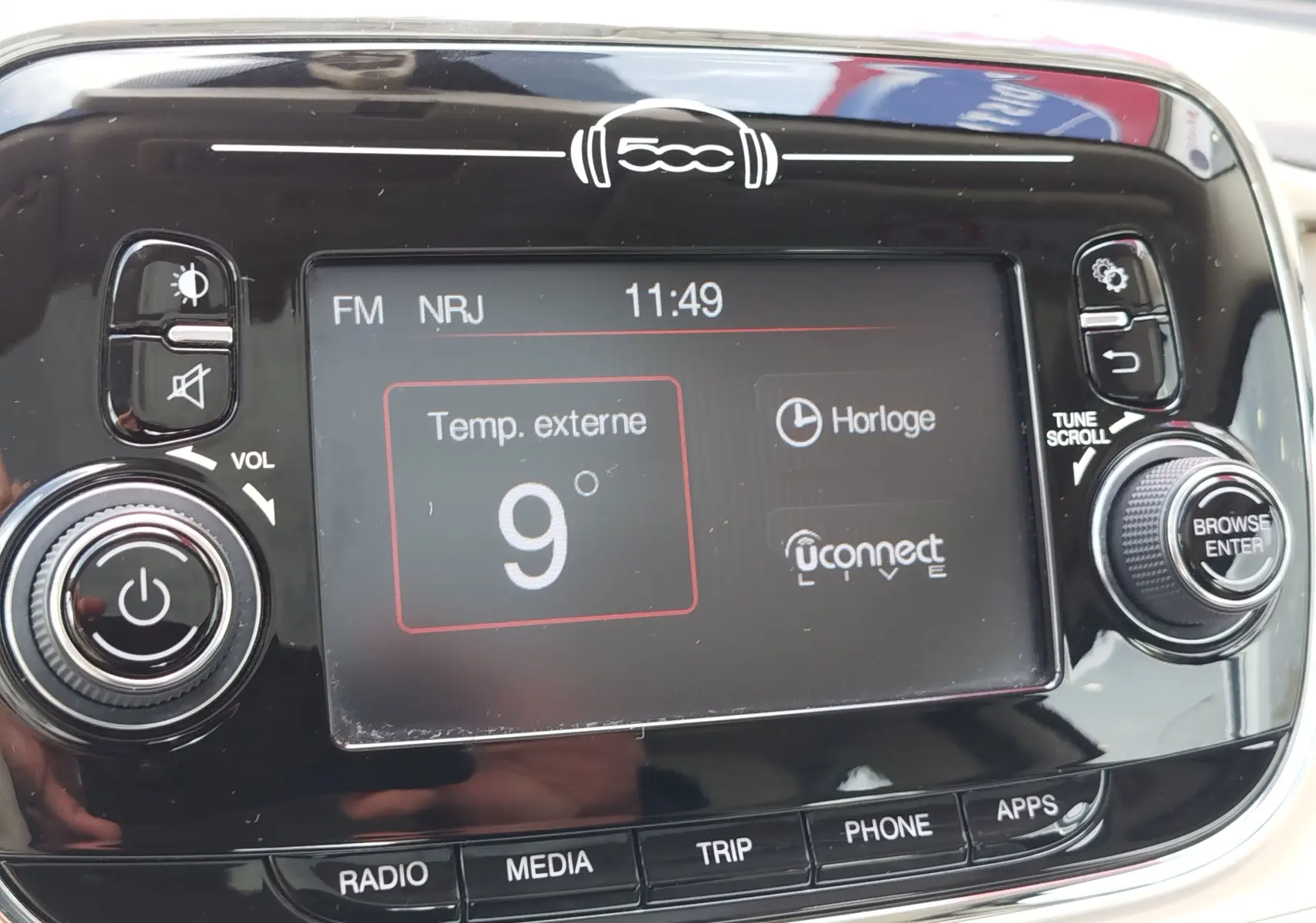 Gros plan sur l’écran tactile central noir brillant de la Fiat 500 blanche, affichant la température extérieure à 9°C.