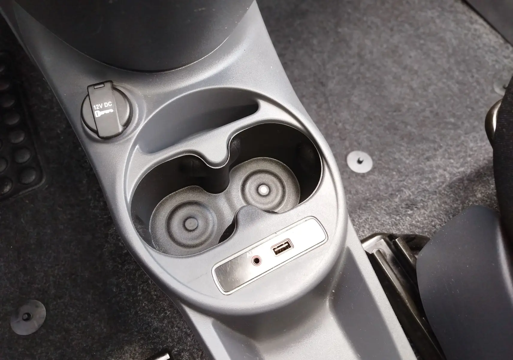 Vue rapprochée de la console centrale et prise 12V dans l'habitacle d'une Fiat 500 blanche de 2017.