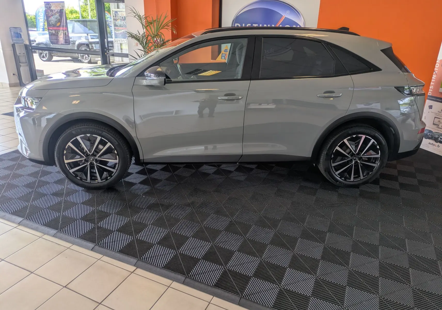 Vue de profil côté gauche du SUV DS7 2025 gris laqué avec jantes alliage 19 pouces dans un showroom.