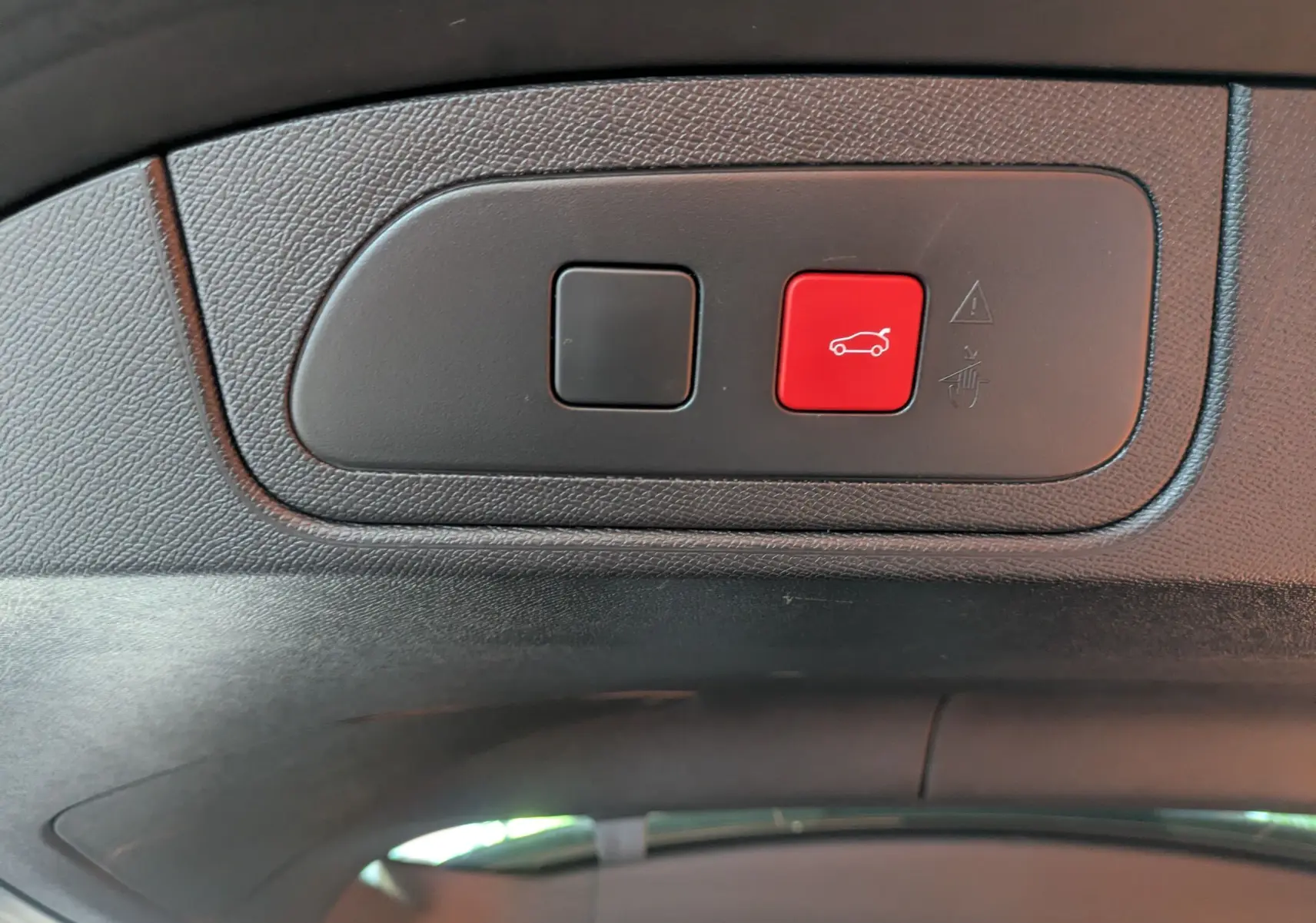 Gros plan sur les boutons du hayon électrique intérieur du DS7 gris laqué, avec un bouton rouge de fermeture.