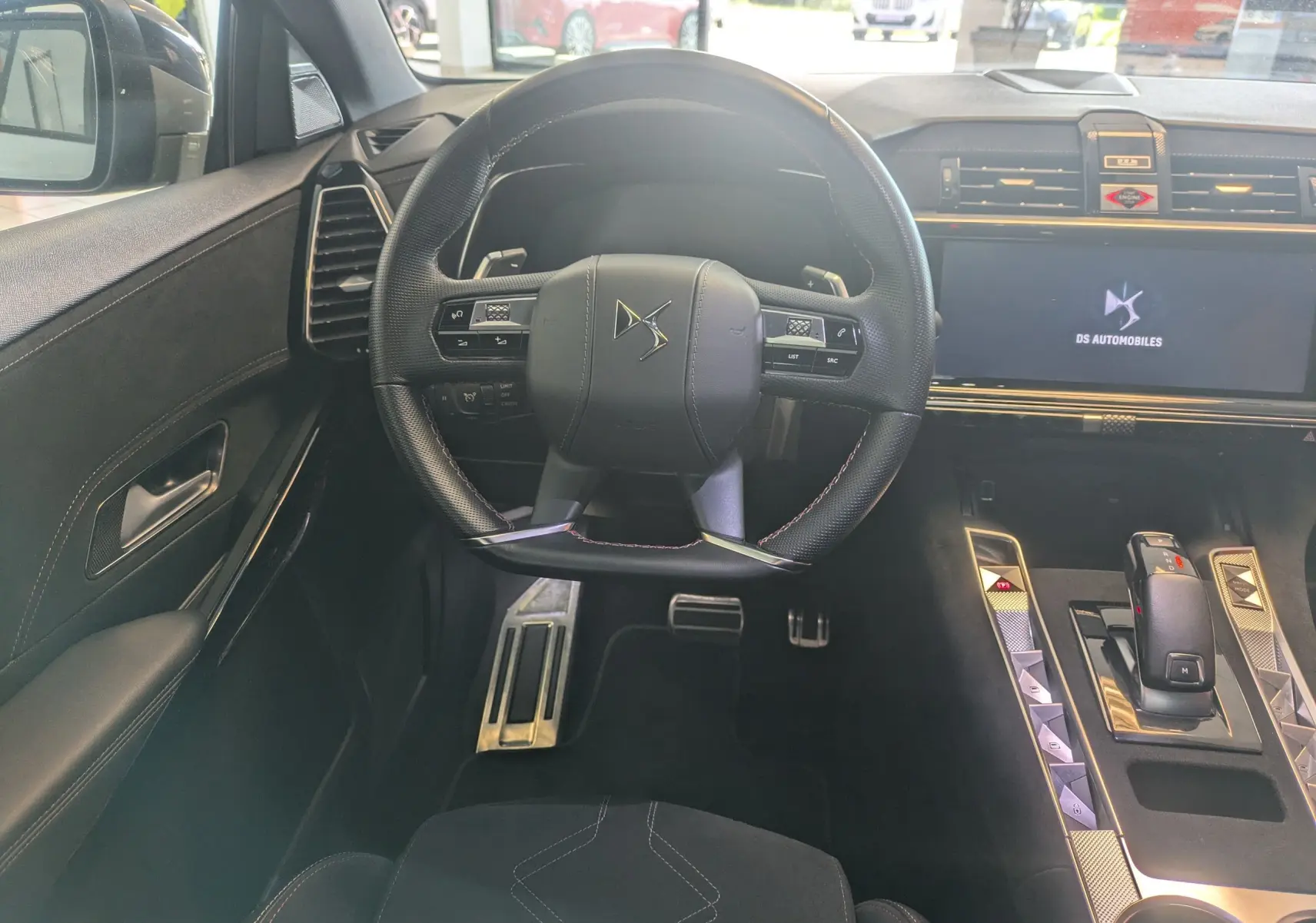 Vue intérieure centrée sur le volant DS noir et la console avec écran tactile affichant DS Automobiles.