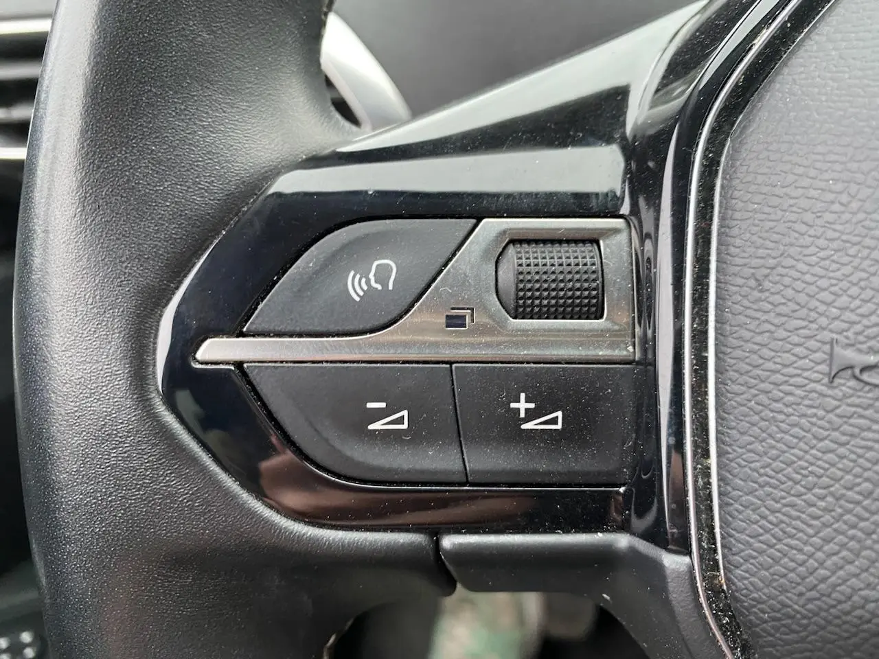 Gros plan sur les commandes de volume et de reconnaissance vocale du volant d'un Peugeot 3008 gris platinium.