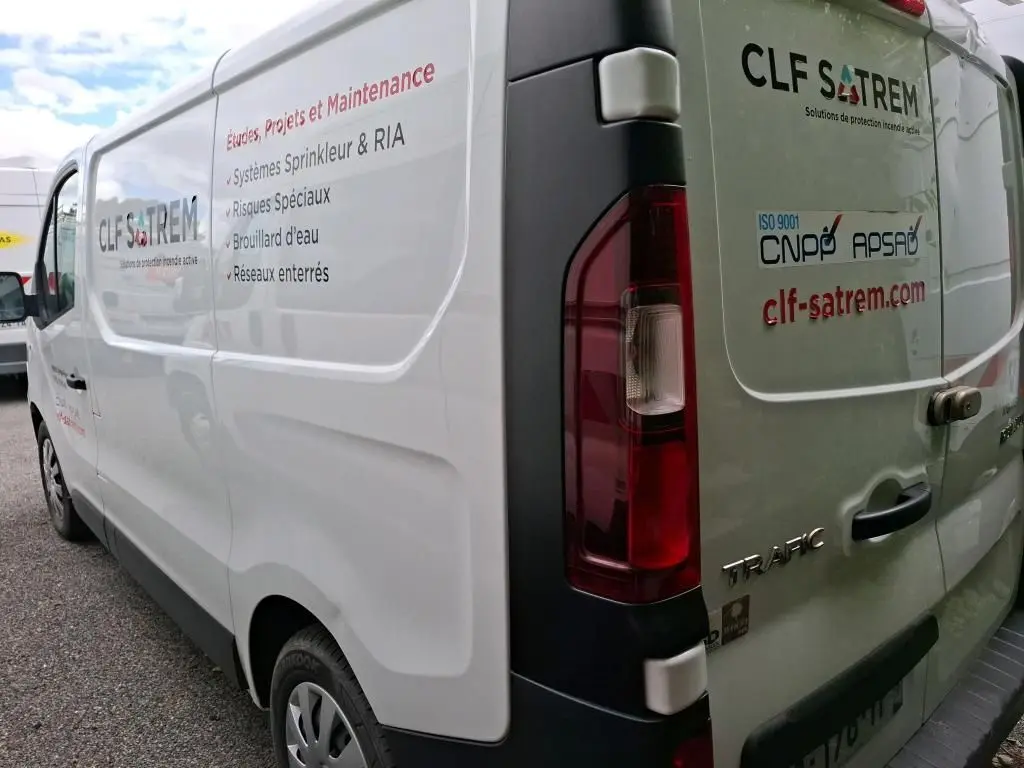 Vue arrière côté droit d'un Renault Trafic blanc avec marquages CLF SATREM et texte technique sur la carrosserie.