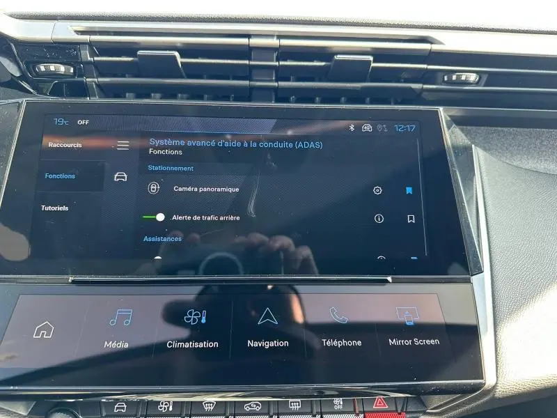 Vue rapprochée de l’écran tactile central du tableau de bord de la Peugeot 308 gris Artense, affichant les aides à la conduite.