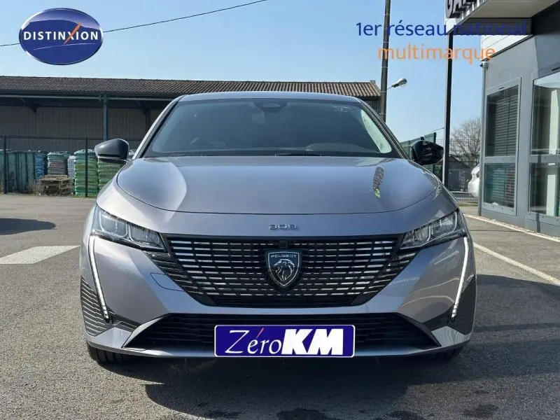 Vue avant frontale d'une Peugeot 308 gris Artense avec calandre noire et feux LED distinctifs.