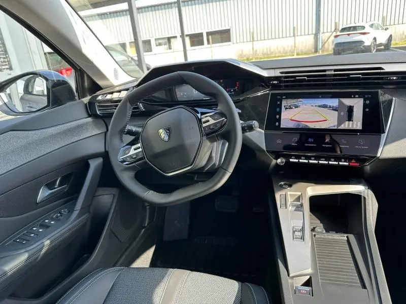 Vue intérieure côté conducteur de la Peugeot 308 gris Artense avec tableau de bord numérique et écran tactile de caméra de recul.