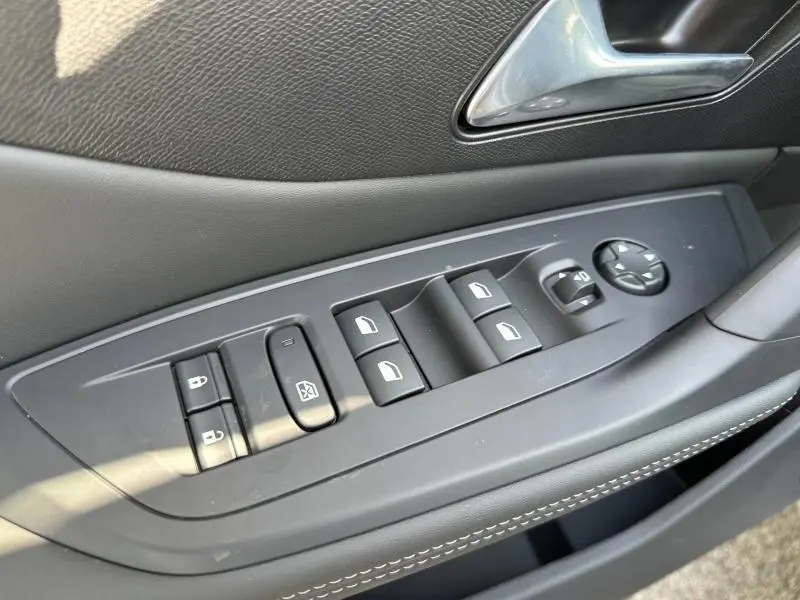 Vue rapprochée des commandes des vitres et rétroviseurs sur la porte côté conducteur d'une Peugeot 308 gris Artense.