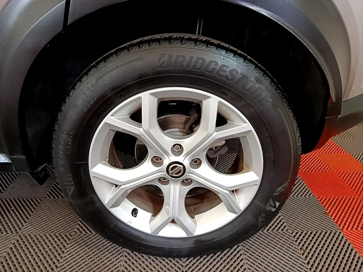 Gros plan sur la roue arrière droite du Nissan Juke gris clair, avec jante argentée et pneu Bridgestone visible.