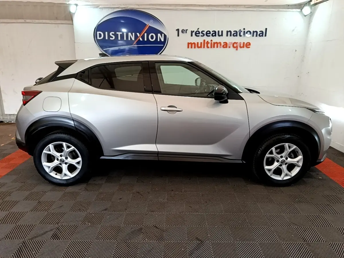 Vue latérale gauche d'un Nissan Juke gris clair 2022 avec jantes alliage et arches de roues noires.