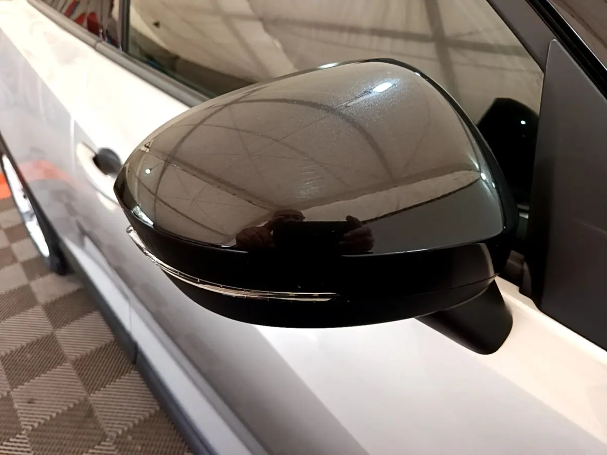 Rétroviseur extérieur droit noir brillant sur Nissan Juke gris clair, vue rapprochée du côté droit.