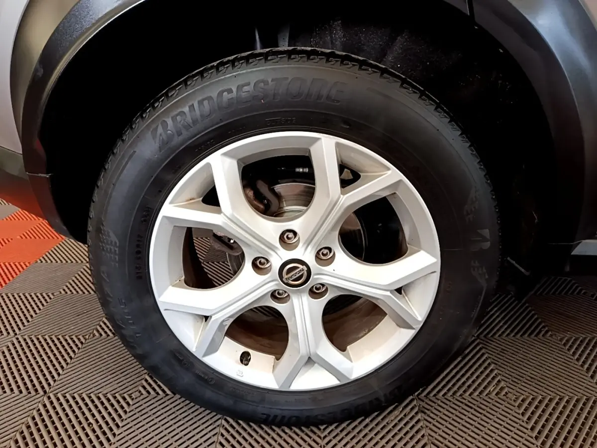 Gros plan sur la roue avant droite du Nissan Juke gris clair avec jante alliage et pneu Bridgestone.