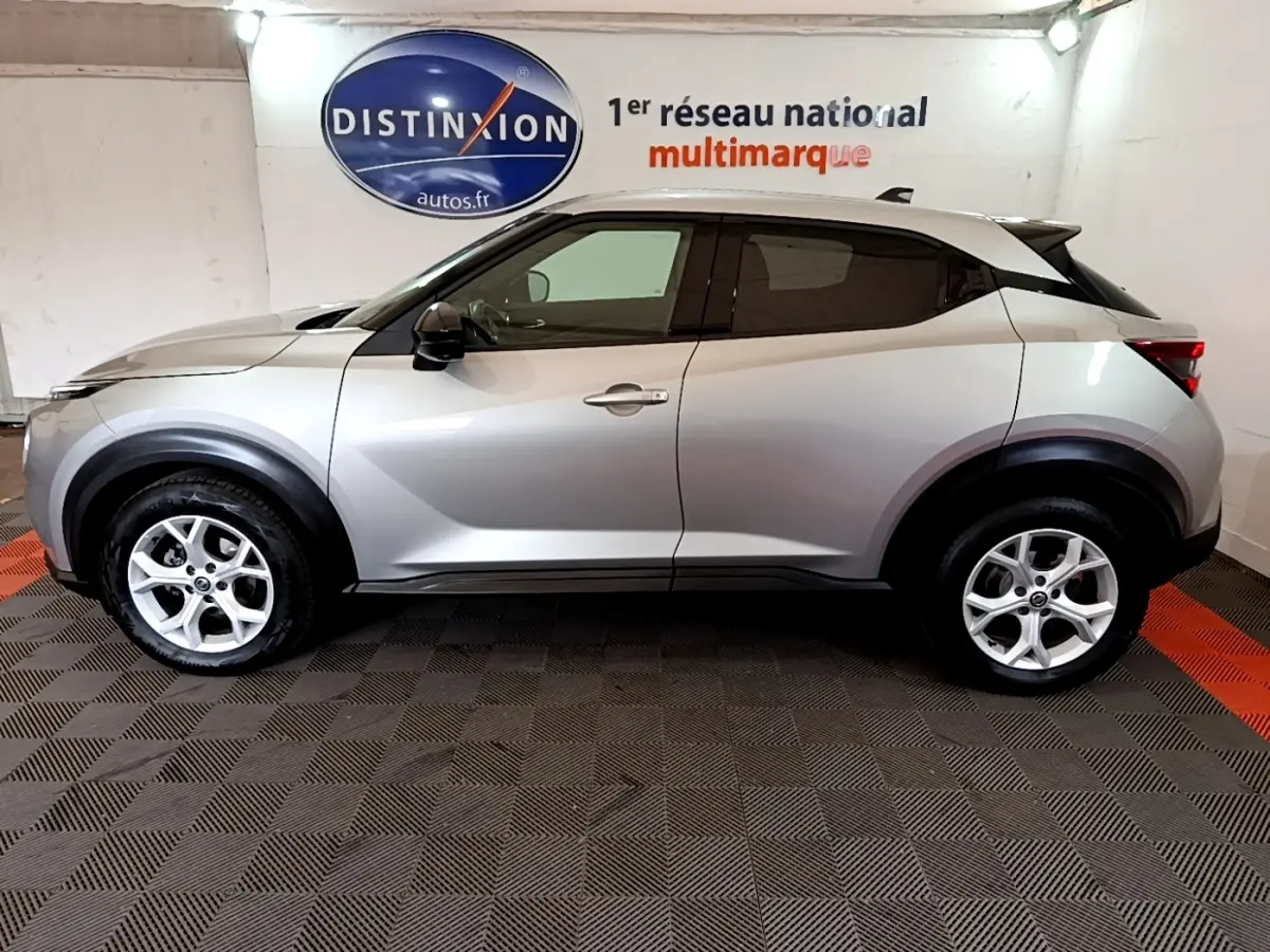 Profil droit du Nissan Juke Business+ 2022 gris clair, avec jantes alliage et rétroviseurs noirs électriques.