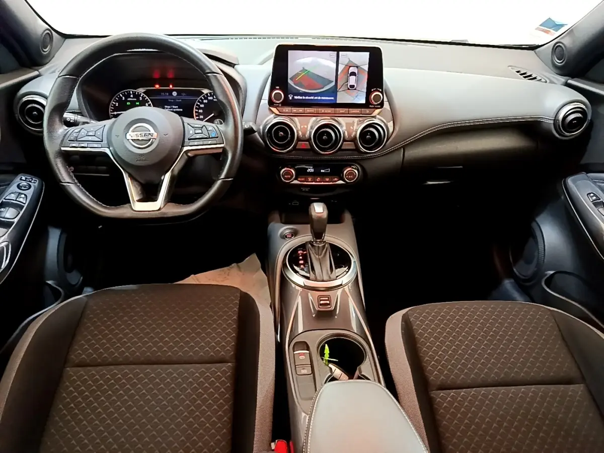 Vue intérieure frontale du tableau de bord et volant cuir noir du Nissan Juke 2022 avec écran tactile et boîte automatique.