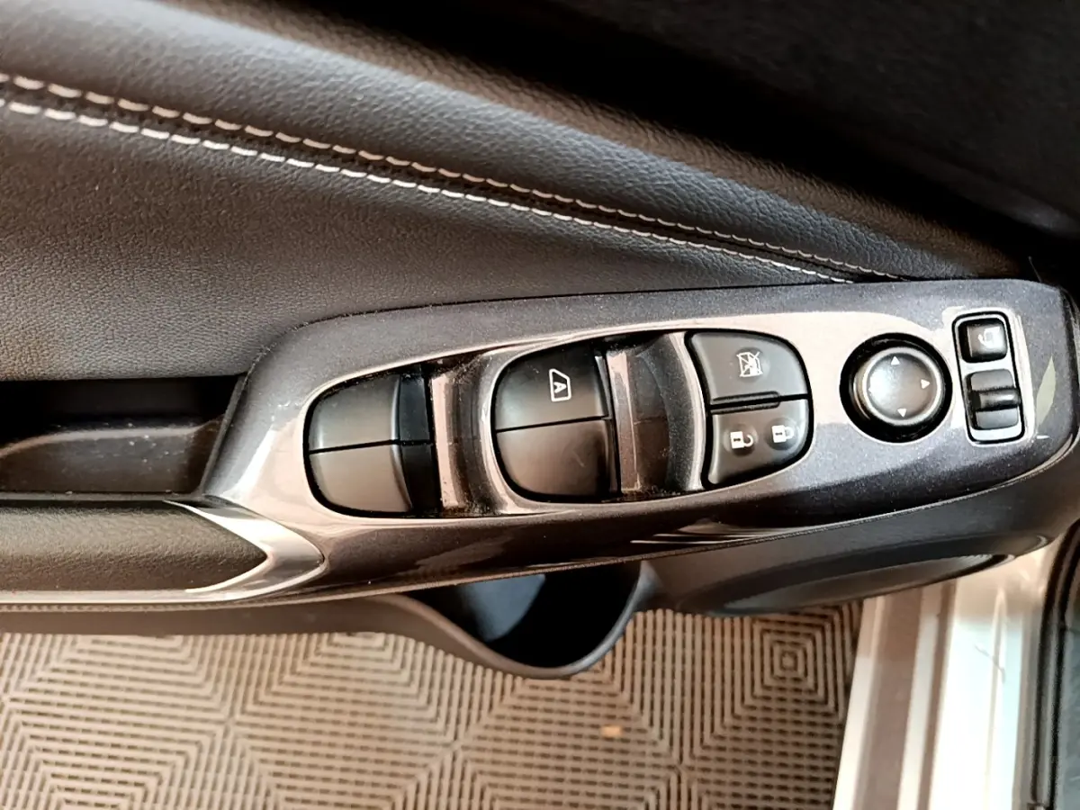 Gros plan sur les commandes de lève-vitres et rétroviseurs côté conducteur d'une Nissan Juke gris clair 2022.