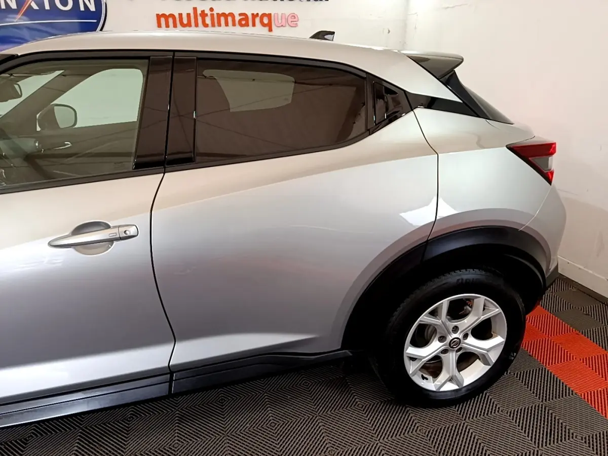 Vue latérale côté droit d'un Nissan Juke gris clair avec jante alliage et poignées ton caisse.