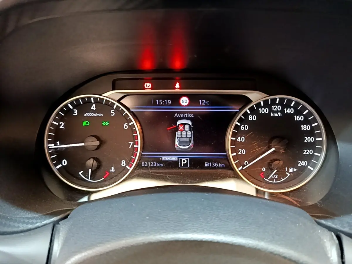 Tableau de bord du Nissan Juke 2022 essence, affichage numérique central avec alertes et compteurs analogiques.