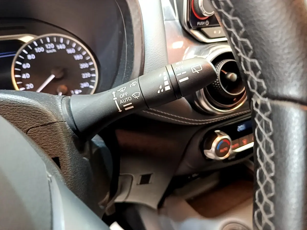 Gros plan sur la manette d’essuie-glace à gauche du volant dans l’habitacle noir du Nissan Juke gris clair 2022.