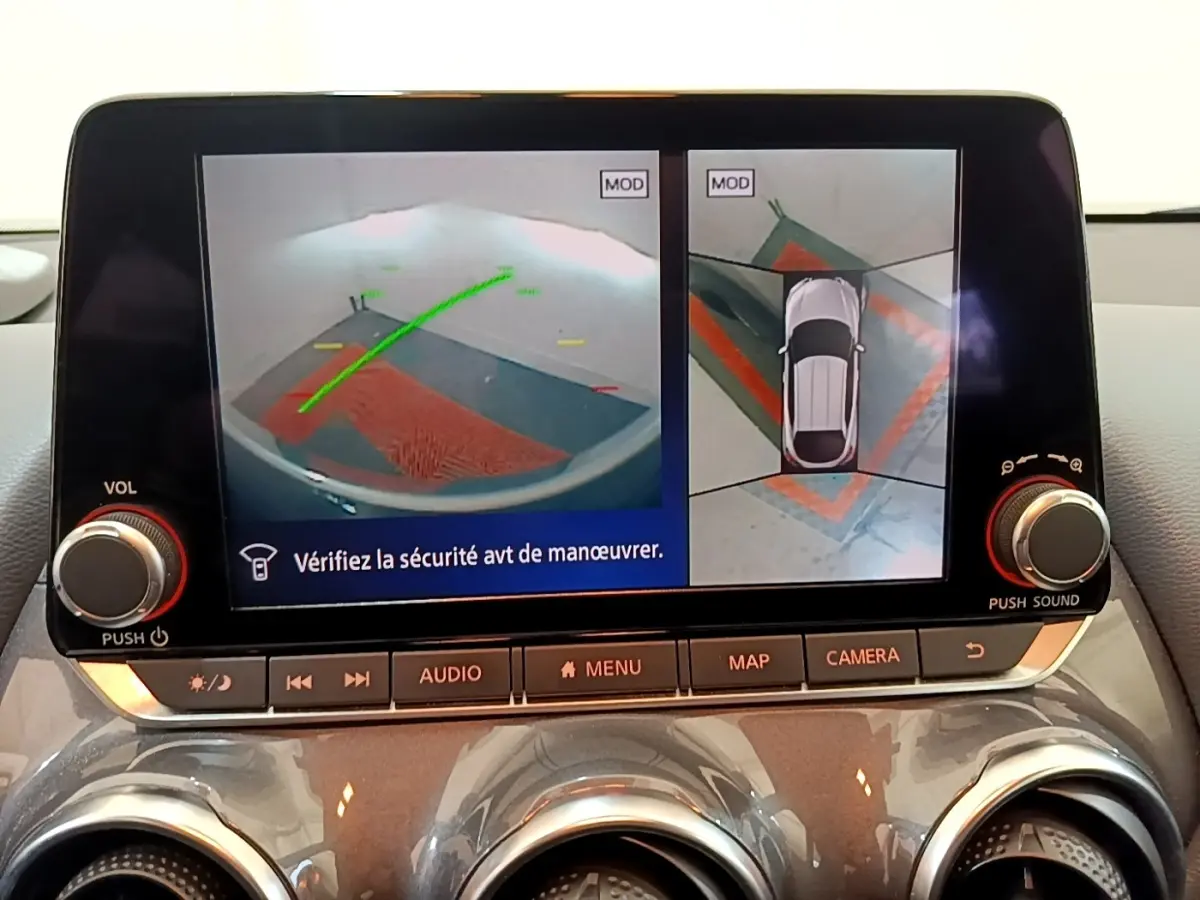 Écran tactile intérieur affichant la caméra 360° et l'aide au stationnement du Nissan Juke gris clair, vue de face.