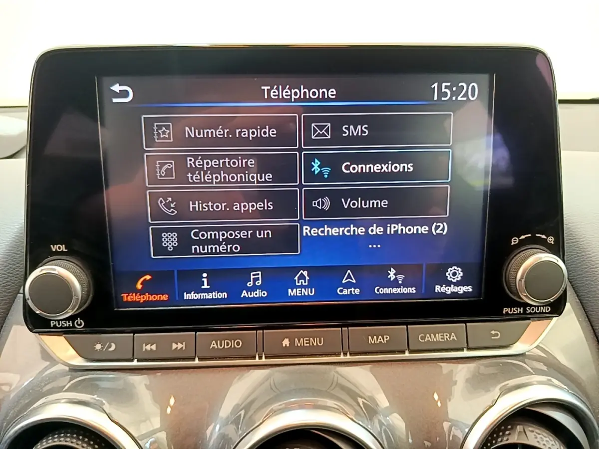 Vue de face du tableau de bord du Nissan Juke gris clair 2022, avec écran tactile multifonctions allumé affichant le menu téléphone.