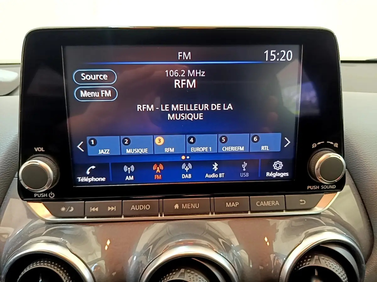 Écran tactile central du tableau de bord du Nissan Juke gris clair, affichant la radio FM à 15h20.