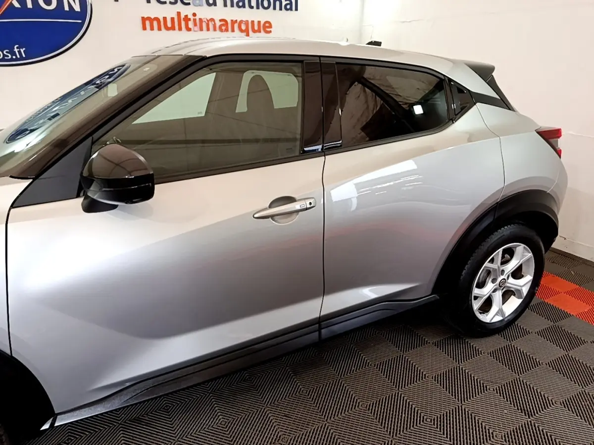 Vue latérale droite d'un Nissan Juke gris clair 2022 avec rétroviseurs noirs et jantes alliage visibles.