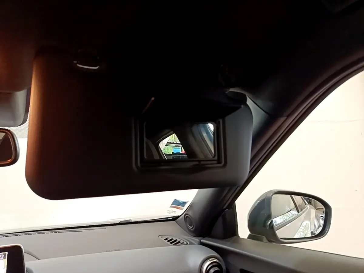 Vue intérieure du pare-soleil côté conducteur avec miroir, rétroviseur extérieur gris clair du Nissan Juke 2022.