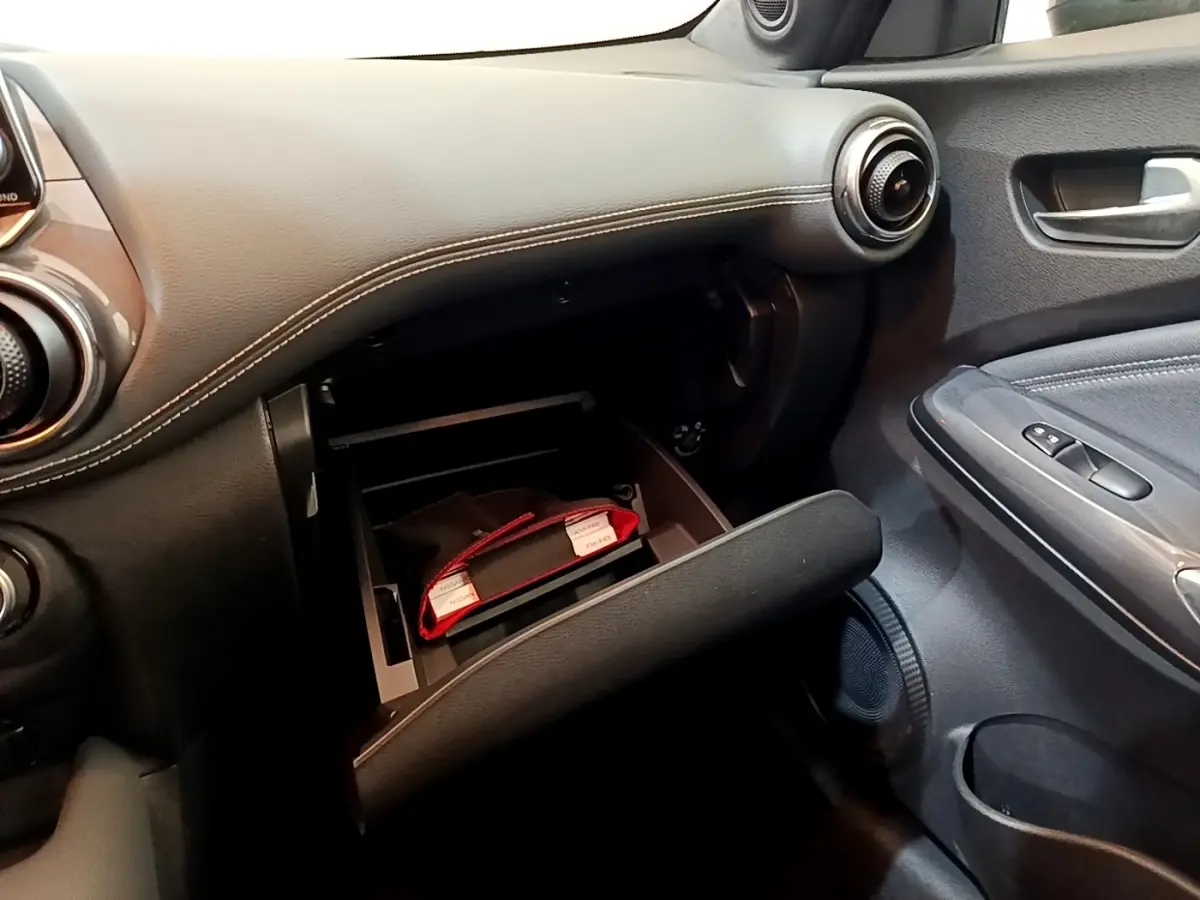 Vue intérieure côté passager du tableau de bord noir avec boîte à gants ouverte du Nissan Juke 2022.