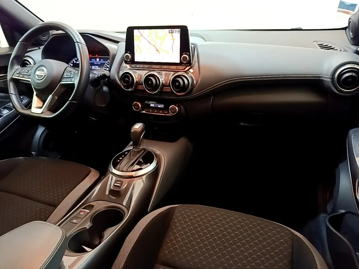 Intérieur du Nissan Juke 2022 gris clair vu de face, avec écran tactile central et console de boîte automatique.