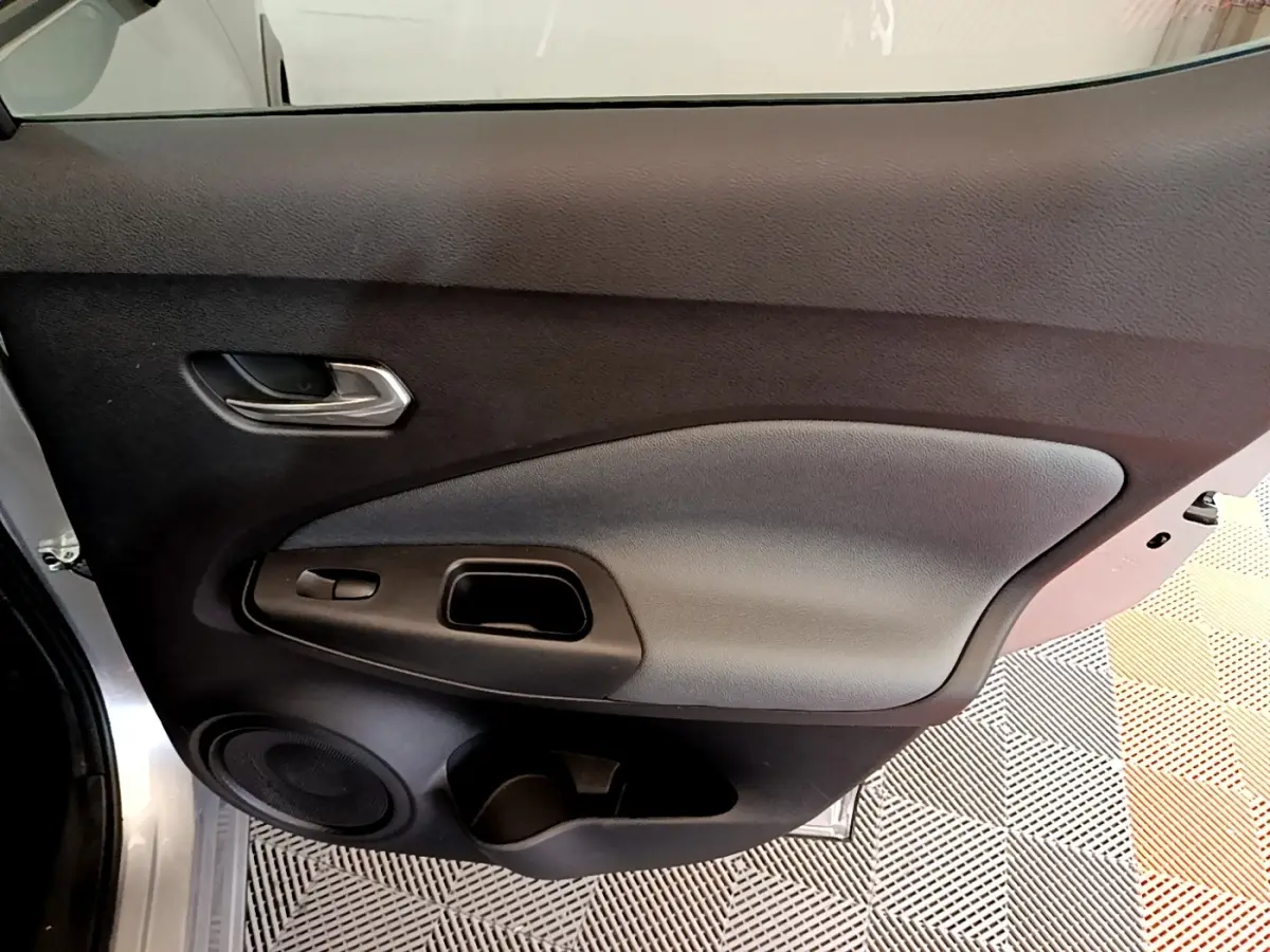 Vue rapprochée de la porte avant gauche gris clair du Nissan Juke 2022 avec poignée et haut-parleur intégrés.