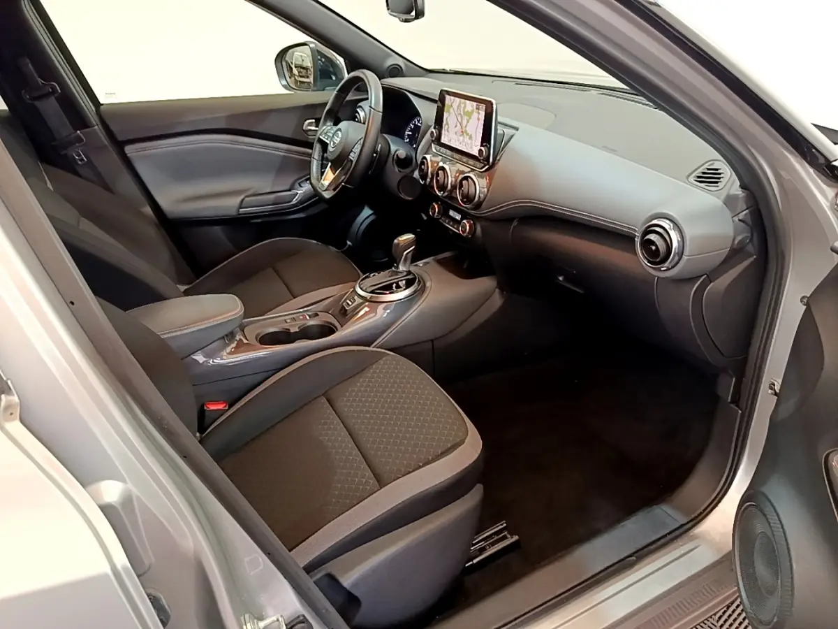 Intérieur avant droit du Nissan Juke gris clair 2022, avec tableau de bord moderne et écran tactile central.