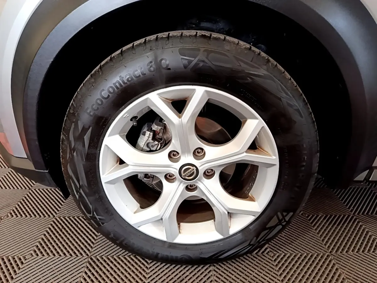 Gros plan sur la roue avant droite d'un Nissan Juke gris clair, avec passage de roue et partie basse de la carrosserie visibles.