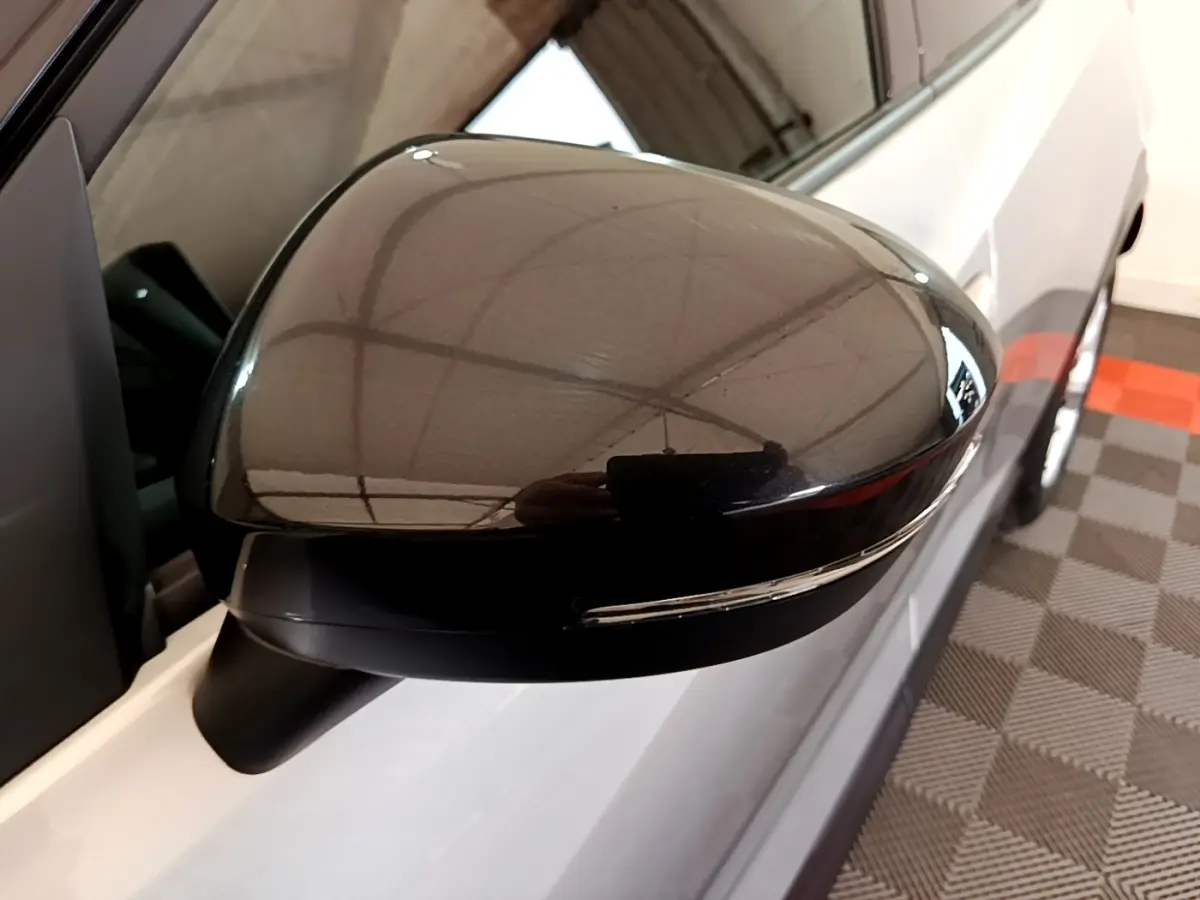 Gros plan sur le rétroviseur droit noir brillant du Nissan Juke gris clair, avec clignotant intégré visible.