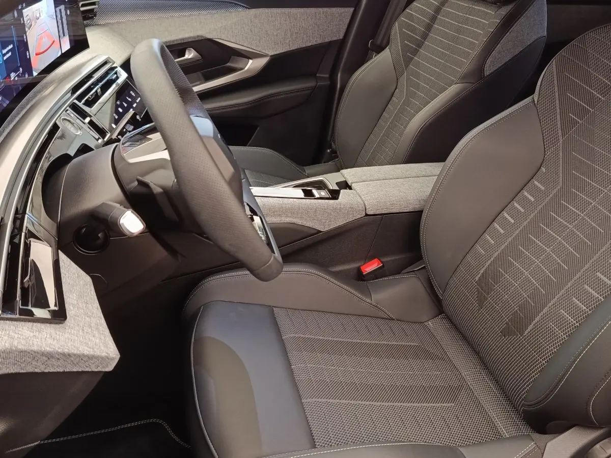 Vue intérieure côté conducteur du Peugeot 3008 Hybrid 2025, sièges tissu et cuir gris avec volant multifonctions cuir.