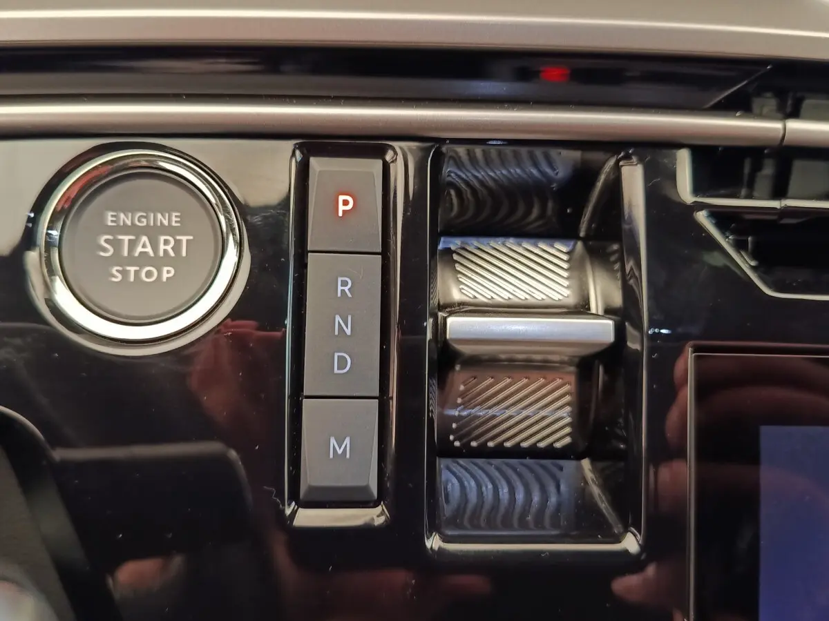 Gros plan sur la console centrale noire brillante du Peugeot 3008 1.2 Hybrid avec bouton start/stop et commande de boîte automatique.