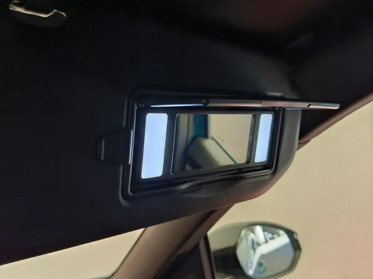 Détail du miroir de courtoisie éclairé sur le pare-soleil côté conducteur d’un Peugeot 3008 bleu.
