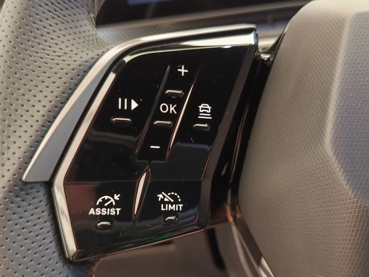 Gros plan sur les commandes multifonctions noires du volant cuir du Peugeot 3008 hybride bleu, côté gauche.