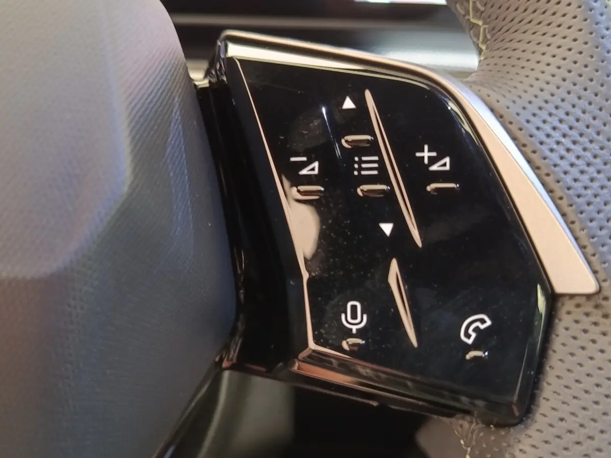 Détail des commandes multifonctions sur le volant cuir perforé du Peugeot 3008 hybride bleu, vue de côté droit.