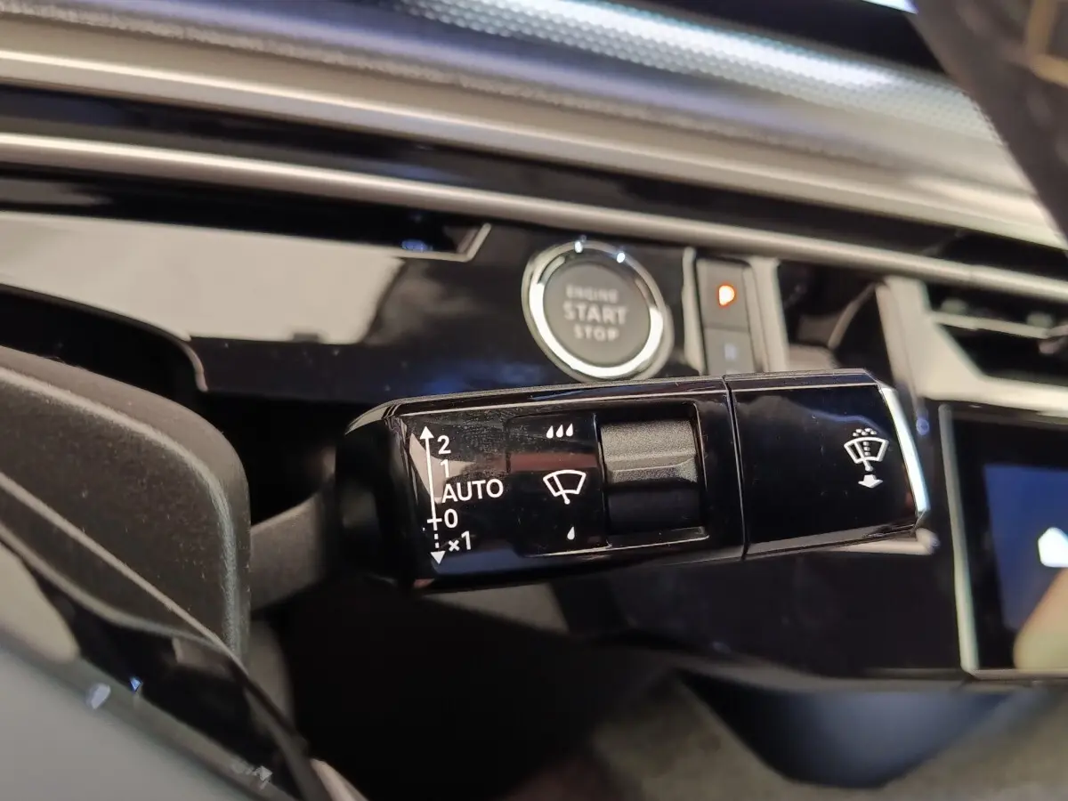 Gros plan sur la commande des essuie-glaces côté gauche du tableau de bord du Peugeot 3008 bleu hybride 2025.