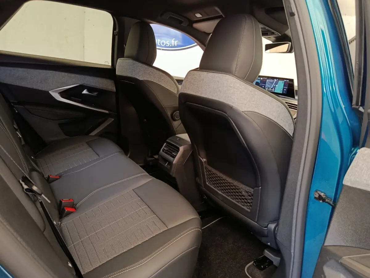 Vue intérieure arrière côté droit du Peugeot 3008 bleu 2025, sièges bi-matière et écran tactile avant visible.