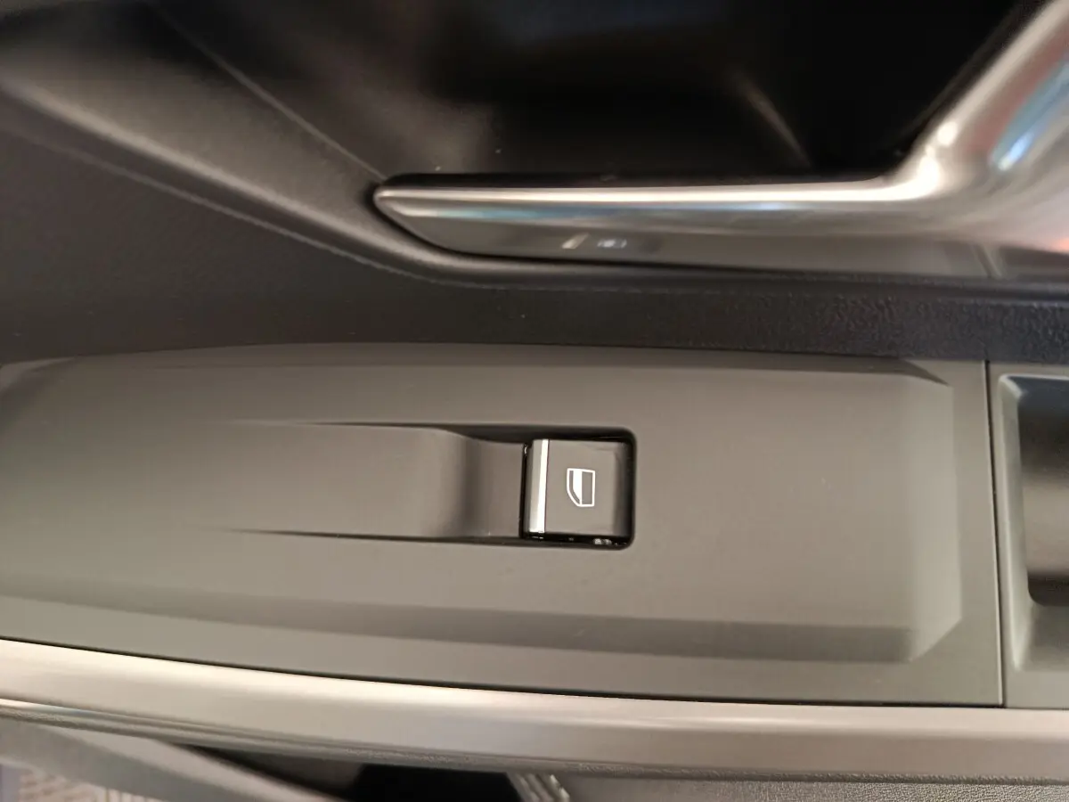 Gros plan sur le bouton de commande de lève-vitre côté conducteur dans l’habitacle du Peugeot 3008 bleu 2025.