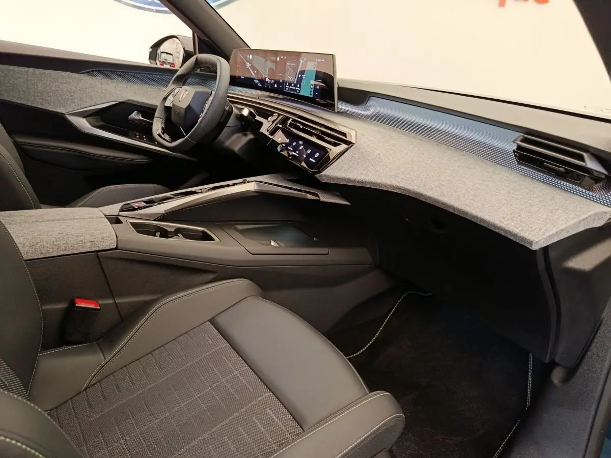 Vue intérieure côté passager du Peugeot 3008 1.2 HYBRID 136 GT avec tableau de bord gris clair et sièges noirs.