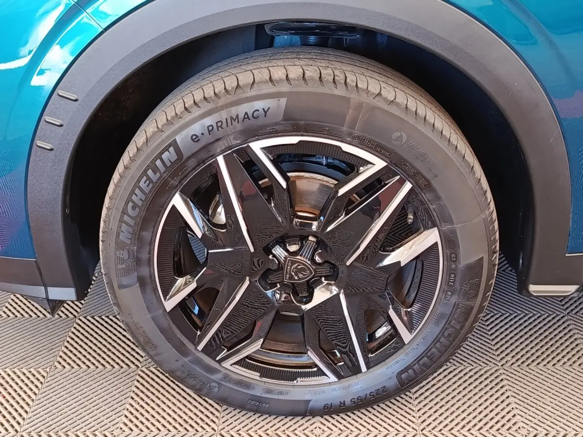 Gros plan sur la roue avant gauche du Peugeot 3008 bleu, mettant en valeur la jante noire et argentée au design moderne.