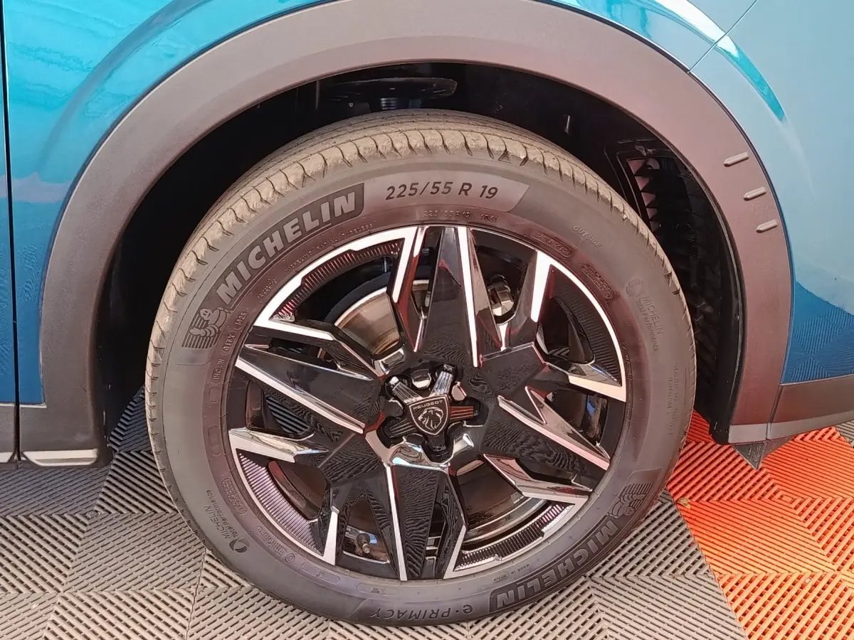 Gros plan sur la roue avant droite du Peugeot 3008 bleu 2025 avec jante noire et détails chromés.