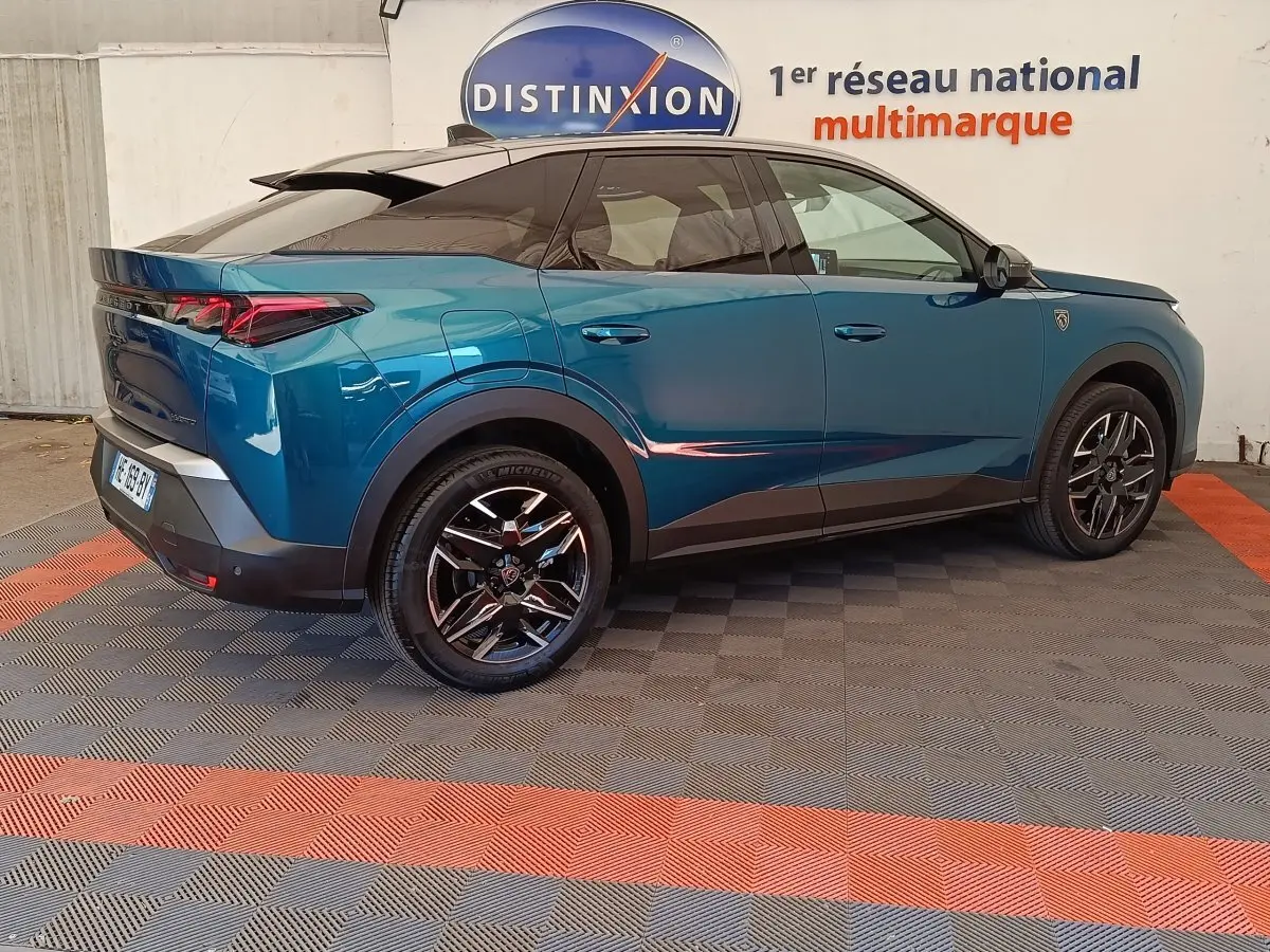 Vue 3/4 arrière droite du Peugeot 3008 bleu 2025 avec jantes noires et toit noir brillant.